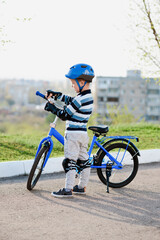 Fototapeta premium Cute child in helmet and protection stands near his bike