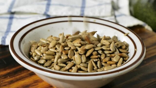Pouring sunflower seeds into a small bowl in super slow motion
