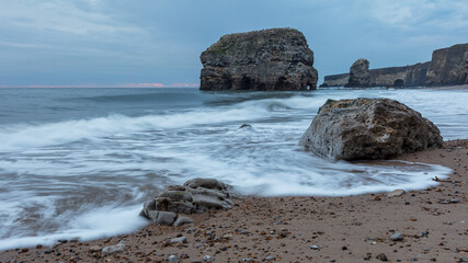 Fototapeta na wymiar Marsden Rock. South Shields, England, in early morning light. With waves washing over the beach and rocks.