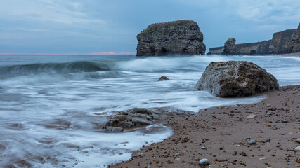 Marsden Rock and cliffs at Marsdean Beach, South Shields, Tyne and Wear, in early morning blue light.
