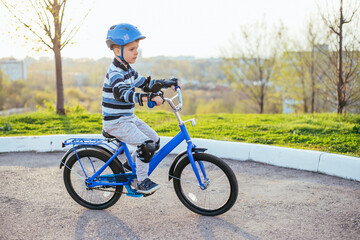 Fototapeta premium A child in a helmet and protection in a bike ride on nature in the spring