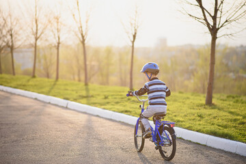 A child in a helmet and protection in a bike ride on nature in the spring