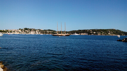 Fototapeta na wymiar Yachts and boats in the harbor. Beautiful panoramic landscape of Villefranche-sur-mer on a sunny day. A wonderful trip to the Cote d'Azur in France. Scenic harbour view of the city of the sea country.