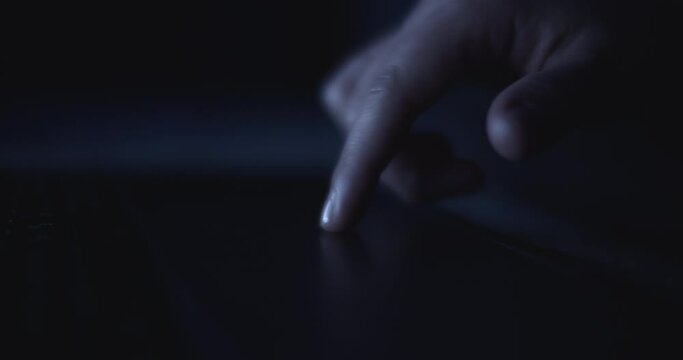 A finger using a computer touchpad to search the internet at night. Slow motion, shallow depth of field, close up. 