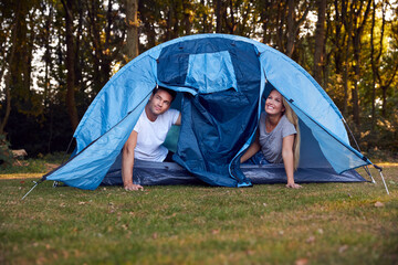 Couple Looking Out Of Tent On Camping Trip In Countryside Together