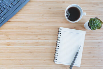 flat lay composition with notebook, pen, coffee, plant, laptop on wood background. top view