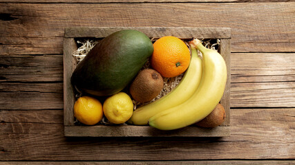 Fresh tropical fruits in a wooden box on a wooden background