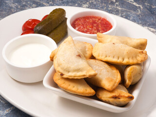 Russian pies with meat posikunchiki with a snack of tomatoes and horseradish and sour cream