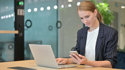 Young Businesswoman using Smartphone and Laptop 