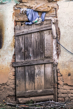 A very old wooden rustic door on a stall in the village on a spring day