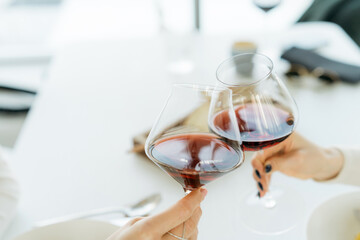 Two women making a celebratory toast with glasses of red wine