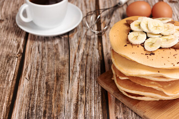 Pancake with bananas on a wooden background, with place for text