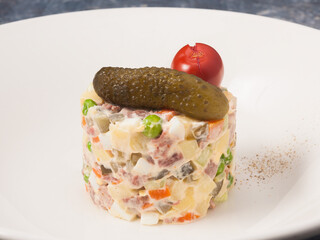 Olivier salad with roast beef on a white plate in a restaurant