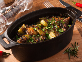 roast in a pot with pickles, cucumbers and potatoes on a wooden Board