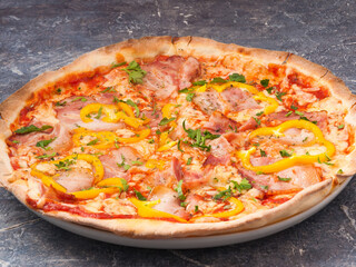 pizza with bacon and bell pepper, tomato sauce, decorated with greens
