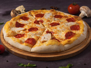 pizza with pepperoni, chicken breast and mozzarella cheese on a wooden Board