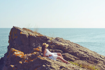 Young Woman Sitting on a Rocks   Above the Sea 