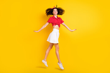 Full size profile photo of cool optimistic brunette hair lady jump go wear red top band skirt isolated on yellow background