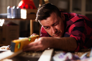 Carpenter working on wood craft at workshop. Young man working in workshop