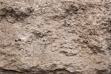 Street gray wall of an old house in close-up, textured background, textured stone