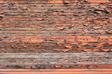 Peeled paint from the sun on the wall, red, textured background, street reading with horizontal lines