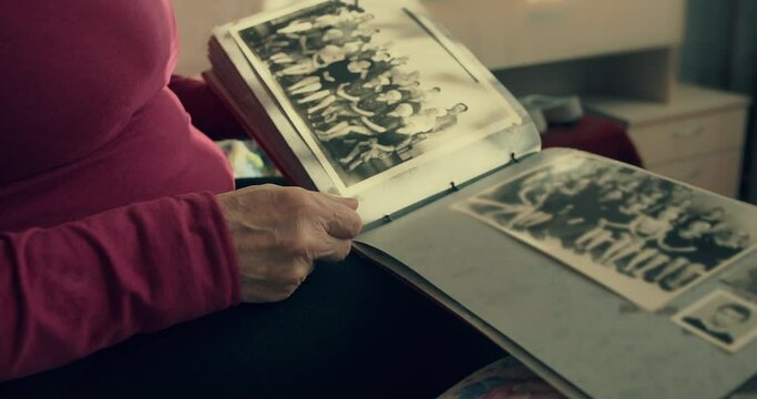 A woman flips through an old photo album and remembers the past. Anastalgia in the old days. A warm sense of the past when viewing old photos. Family photo album