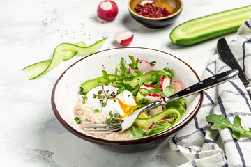 oatmeal porridge breakfast with poached egg and fresh vegetables. Healthy balanced food. Food recipe background. Close up