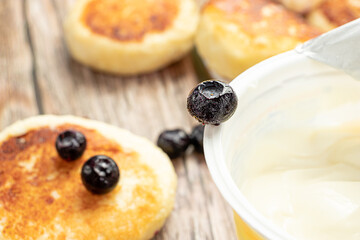 Frozen blueberries in a close-up, on the background of curd pancakes