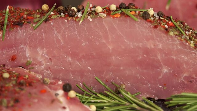 Close up of fresh raw pork with spices and seasonings is sprinkled with salt. Food concept, cooking meat steak.