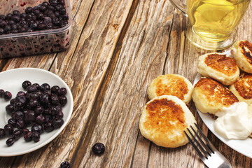 Cottage cheese pancakes with frozen blueberries on a wooden background in a close-up, with space for text