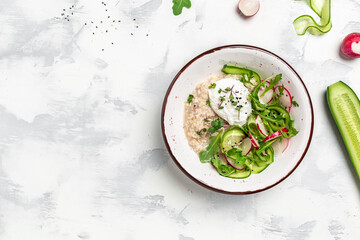 Breakfast oatmeal porridge with poached egg with vegetable salad of radish, cucumbers, arugula and microgreens. Healthy balanced food. banner, menu recipe place for text, top view