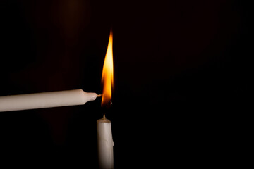 Lighting a candle  from another candle in the black background. A practice done during Christian...
