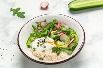oatmeal porridge breakfast with poached egg and fresh vegetables. Healthy balanced food. Food recipe background. Close up