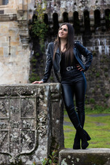 portrait of pretty young brunette woman dressed in a leather jacket in front of an old castle