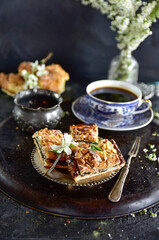 Poppy seed cake in pieces on a silver plate with morning coffee on a black background.