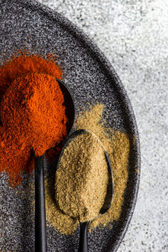 Spoonful of khmeli suneli spice mix and a spoonful of blue fenugreek on a plate