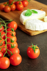Cherry tomatoes on a branch, a tomato in a close-up on a dark background, still life