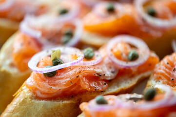 Home made fresh salmon with baked baguette, butter, red onion, black pepper and capers. Selective focus