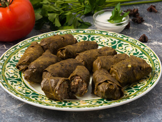 dolma on a plate with sauce decorated with vegetables