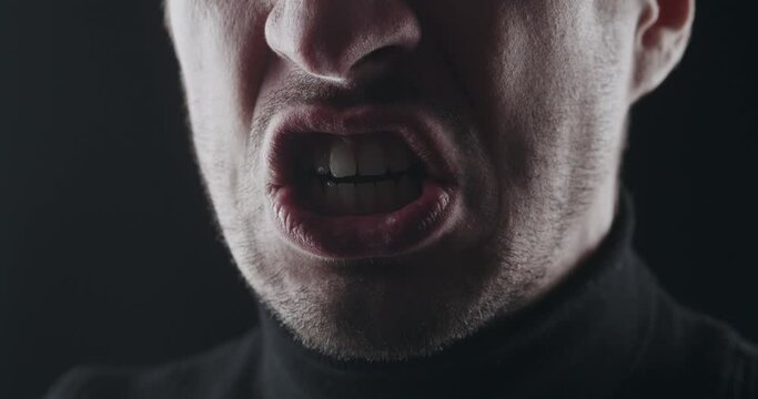 Close-up of aggressive man's mouth screams and threatens with violence. Macro shot of mad boss shows anger at employees. Angry brutal male intimidatingly shows rage. Demonic face with hatred