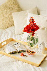 Still life details in home interior of living room. Open book and vase red tulips. Read and rest.