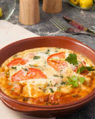 omelet with tomatoes and herbs in a clay plate