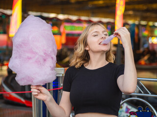 Mujer joven comiendo algodón de azúcar en la feria