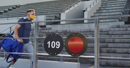 Caucasian disabled male athlete with prosthetic leg wearing face mask, walking - Powered by Adobe
