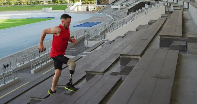 Caucasian disabled male athlete with prosthetic leg training, running up stairs
