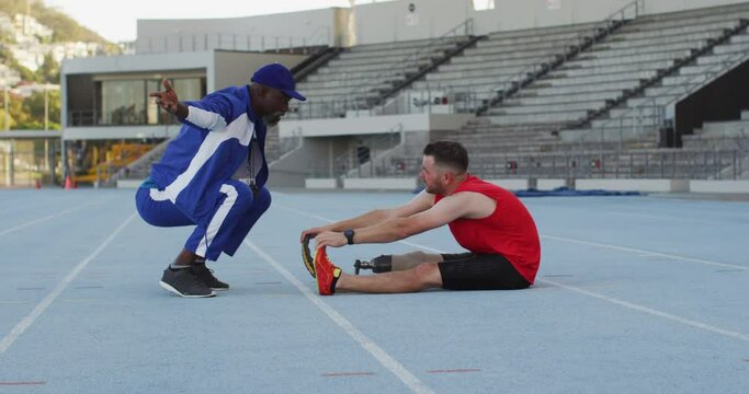 Diverse male coach and disabled athlete with prosthetic leg training and stretching