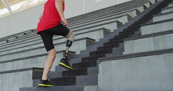 Caucasian disabled male athlete with prosthetic leg training, running up stairs