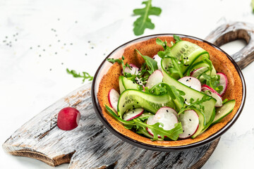 Green vegan salad from green leaves mix and vegetables. salad of radish, cucumbers, arugula. Healthy vegan food. place for text, top view