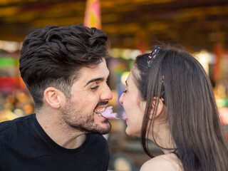 Pareja joven disfrutando de la feria comiendo algodón de azúcar 