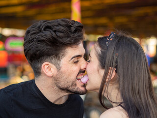 Pareja joven disfrutando de la feria comiendo algodón de azúcar 